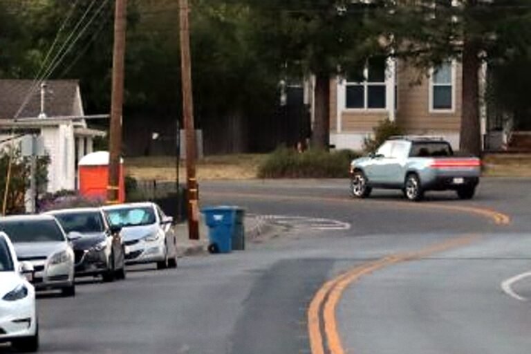 A silver Rivian pickup rounds a curve on a residential street in Healdsburg